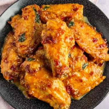 Plate of golden Honey Garlic Chicken Wings garnished with green onions