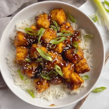 Plate of Honey Garlic Tofu garnished with green onions and sesame seeds.