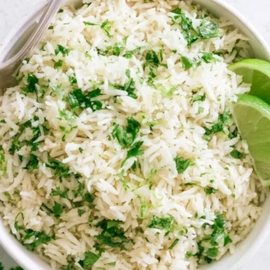 Bowl of cilantro lime rice garnished with fresh cilantro and lime wedges.