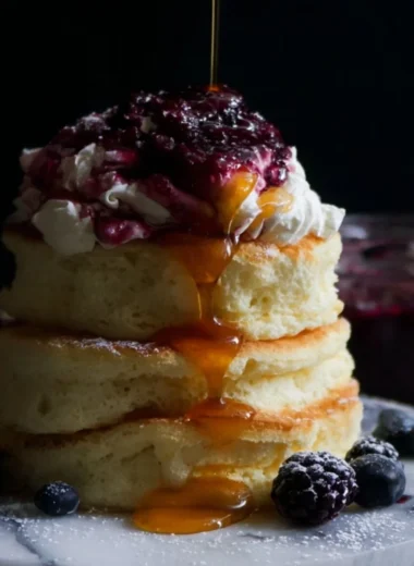 Fluffy Japanese soufflé pancakes served with syrup and fruit