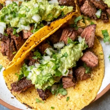 Delicious grilled steak tacos garnished with avocado salsa on a plate