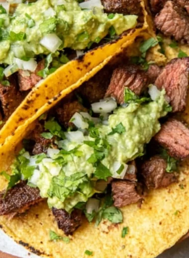 Delicious grilled steak tacos garnished with avocado salsa on a plate