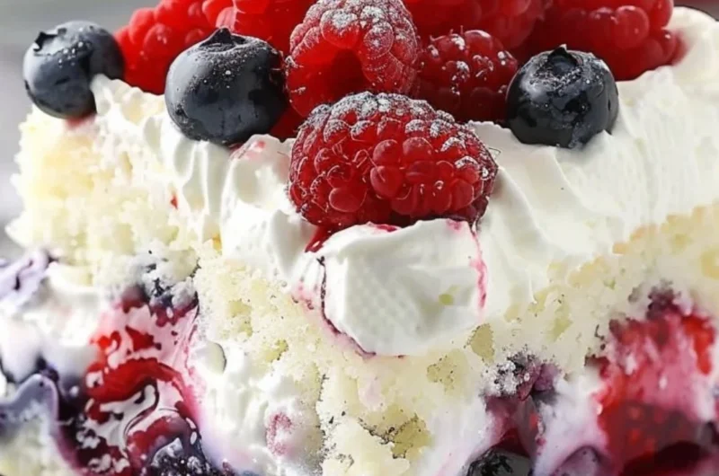 Delicious Summer Berry Poke Cake topped with vibrant mixed berries.