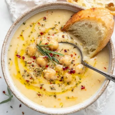Vegan garlic chickpea soup garnished with herbs in a bowl
