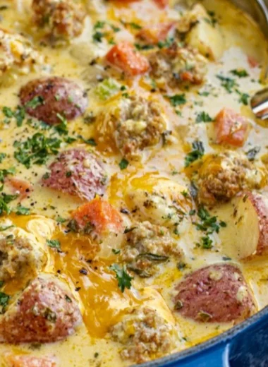Bowl of creamy sausage potato soup with fresh herbs on top