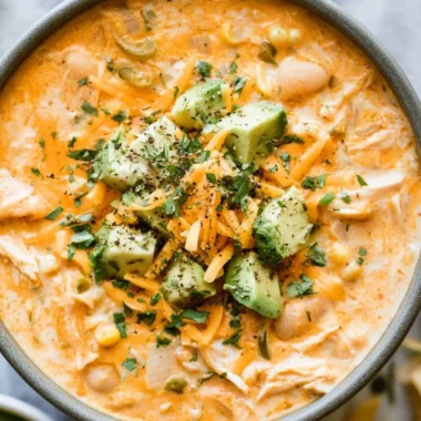 Bowl of creamy white chicken chili garnished with cilantro and lime wedges
