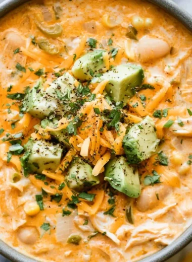Bowl of creamy white chicken chili garnished with cilantro and lime wedges
