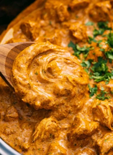 Delicious crockpot butter chicken served with rice and garnished with cilantro.