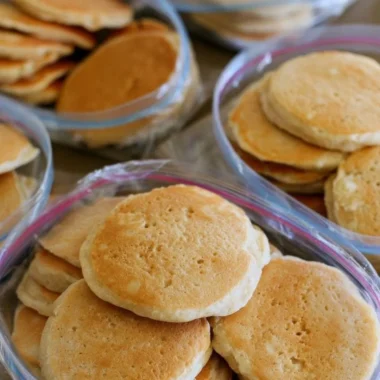 A stack of easy freezer pancakes served with syrup and berries.