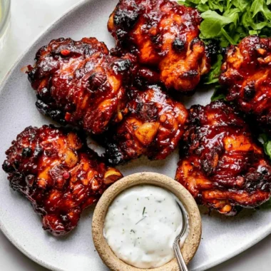 Baked Honey Harissa Chicken garnished with fresh herbs on a serving platter.