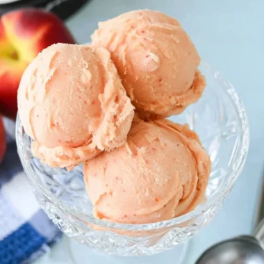 Delicious homemade peach sorbet served in a bowl with fresh peaches