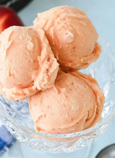 Delicious homemade peach sorbet served in a bowl with fresh peaches
