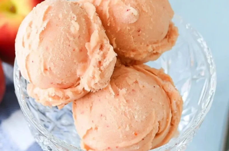 Delicious homemade peach sorbet served in a bowl with fresh peaches