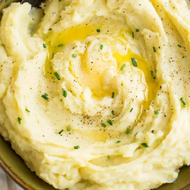 Bowl of perfect creamy mashed potatoes with butter and parsley garnish