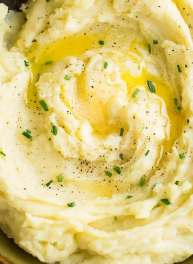 Bowl of perfect creamy mashed potatoes with butter and parsley garnish