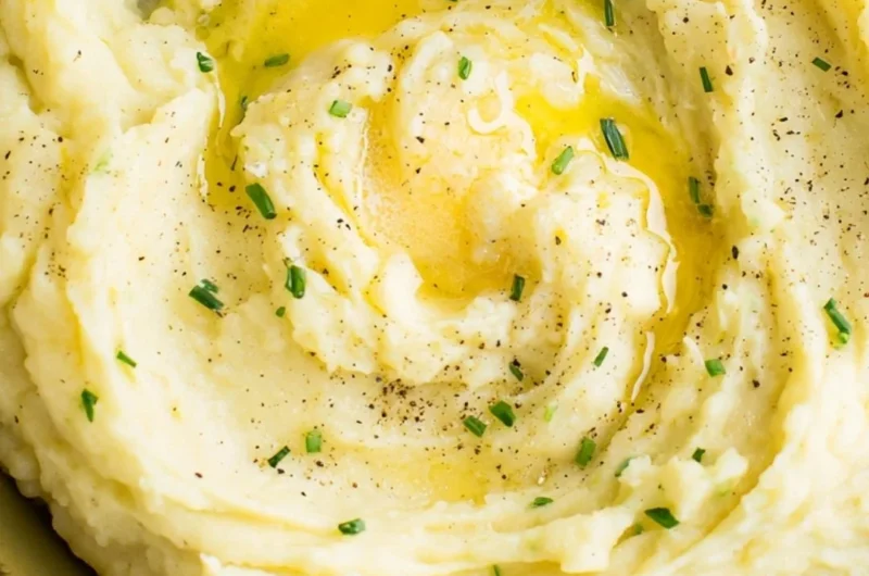 Bowl of perfect creamy mashed potatoes with butter and parsley garnish