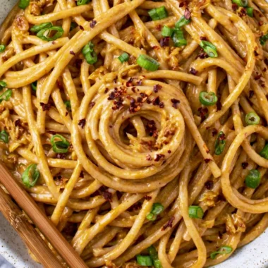 Plate of vegan garlic noodles garnished with herbs and vegetables