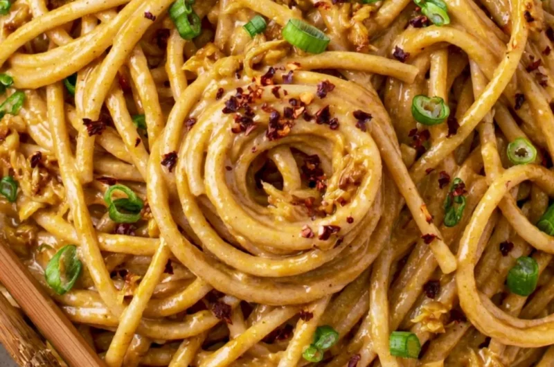 Plate of vegan garlic noodles garnished with herbs and vegetables