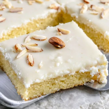 A delicious slice of White Texas Almond Sheet Cake topped with almond frosting.