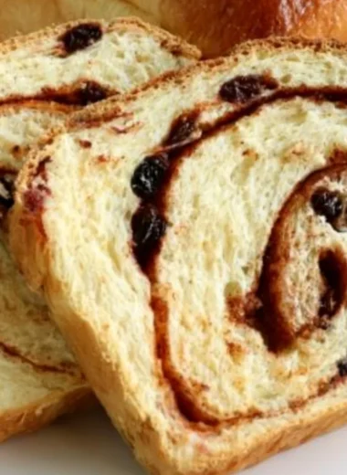 Loaf of homemade cinnamon swirl raisin bread on a wooden cutting board