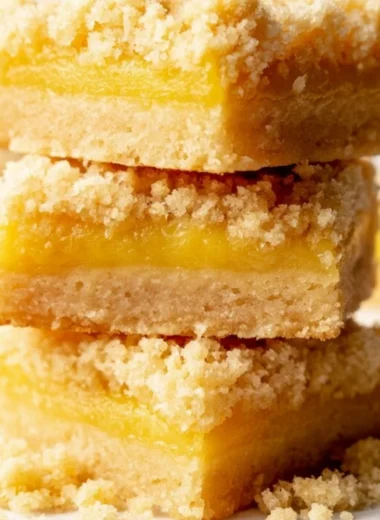 Delicious lemon curd bars on a white plate, garnished with lemon slices.