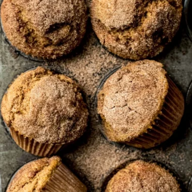 Pumpkin Snickerdoodle Muffins with cinnamon sugar on a wooden table